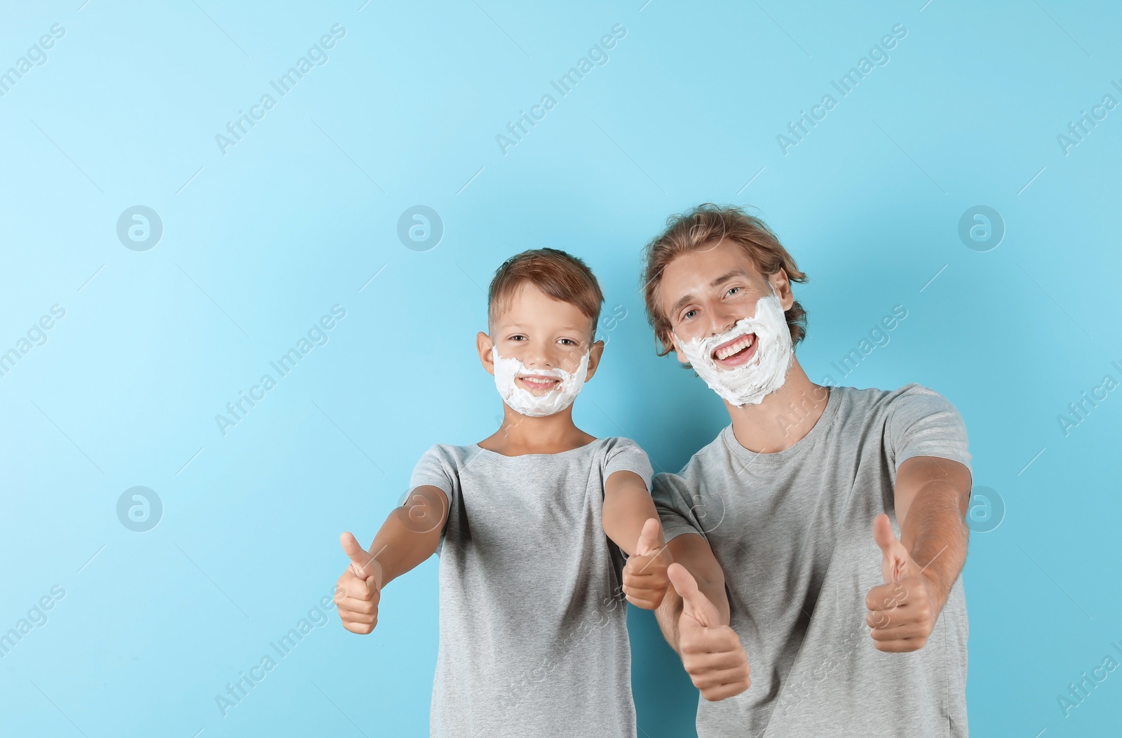 Photo of Father and son with shaving foam on faces against color background, space for text