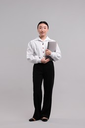 Photo of Full length portrait of businesswoman with laptop on grey background