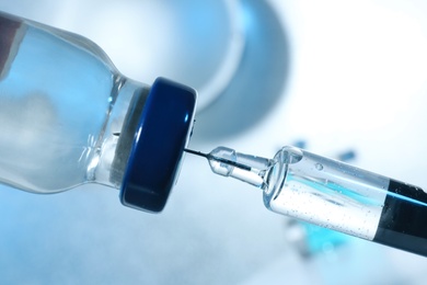 Photo of Filling syringe with COVID-19 vaccine on blurred background, closeup