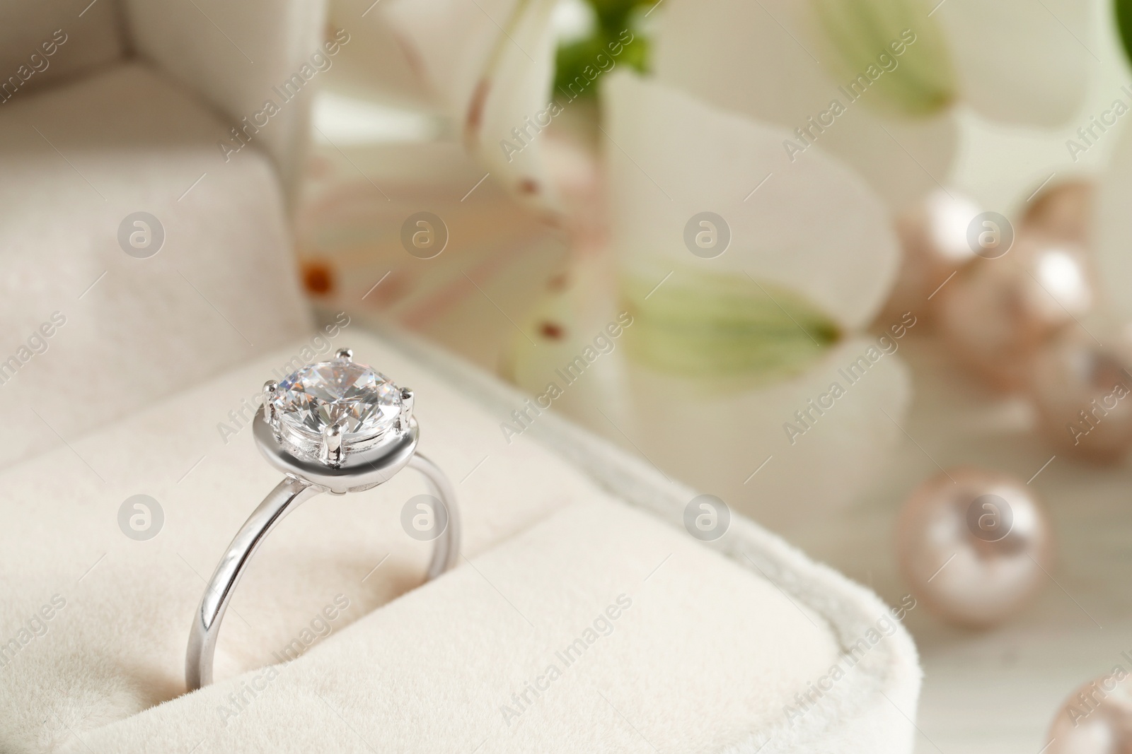 Photo of Beautiful engagement ring in box against blurred background, closeup. Space for text