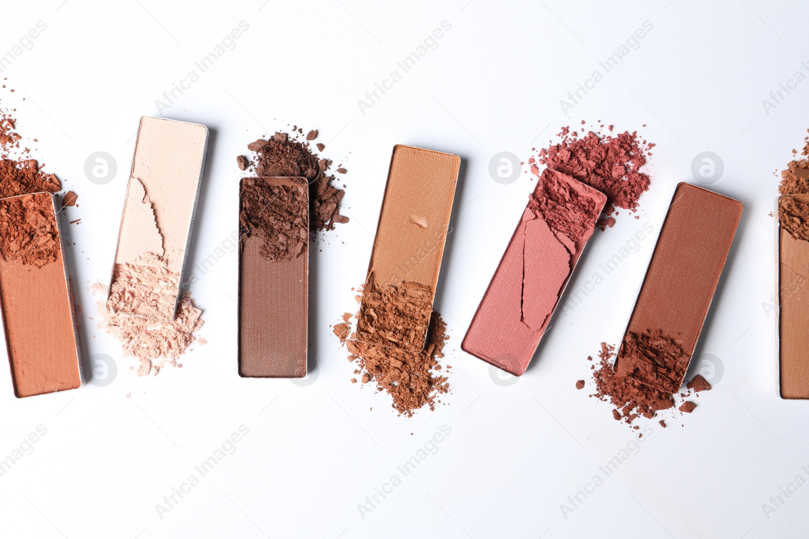 Photo of Different crushed eye shadows on white background, flat lay. Professional makeup product