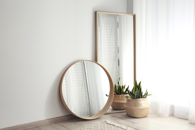 Photo of Mirrors and potted plant near window in light room