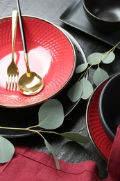 Stylish ceramic plates, cutlery and floral decor on grey table