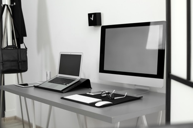 Photo of Modern workplace interior with computers on table. Space for text