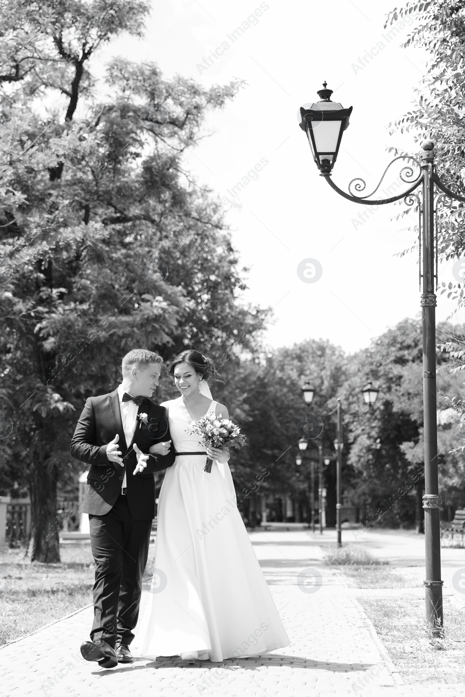 Photo of Happy newlyweds walking outdoors, black and white effect