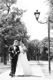 Happy newlyweds walking outdoors, black and white effect