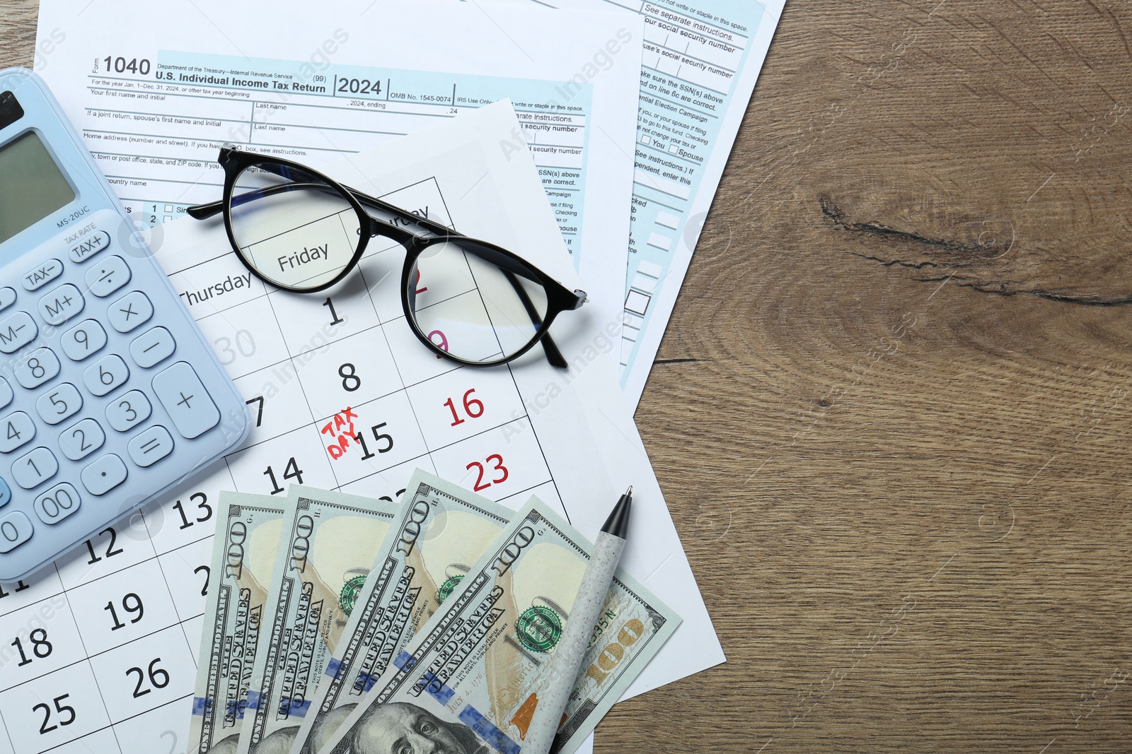 Photo of Calendar with date reminder about tax day, documents, money, calculator and glasses on wooden table, top view. Space for text