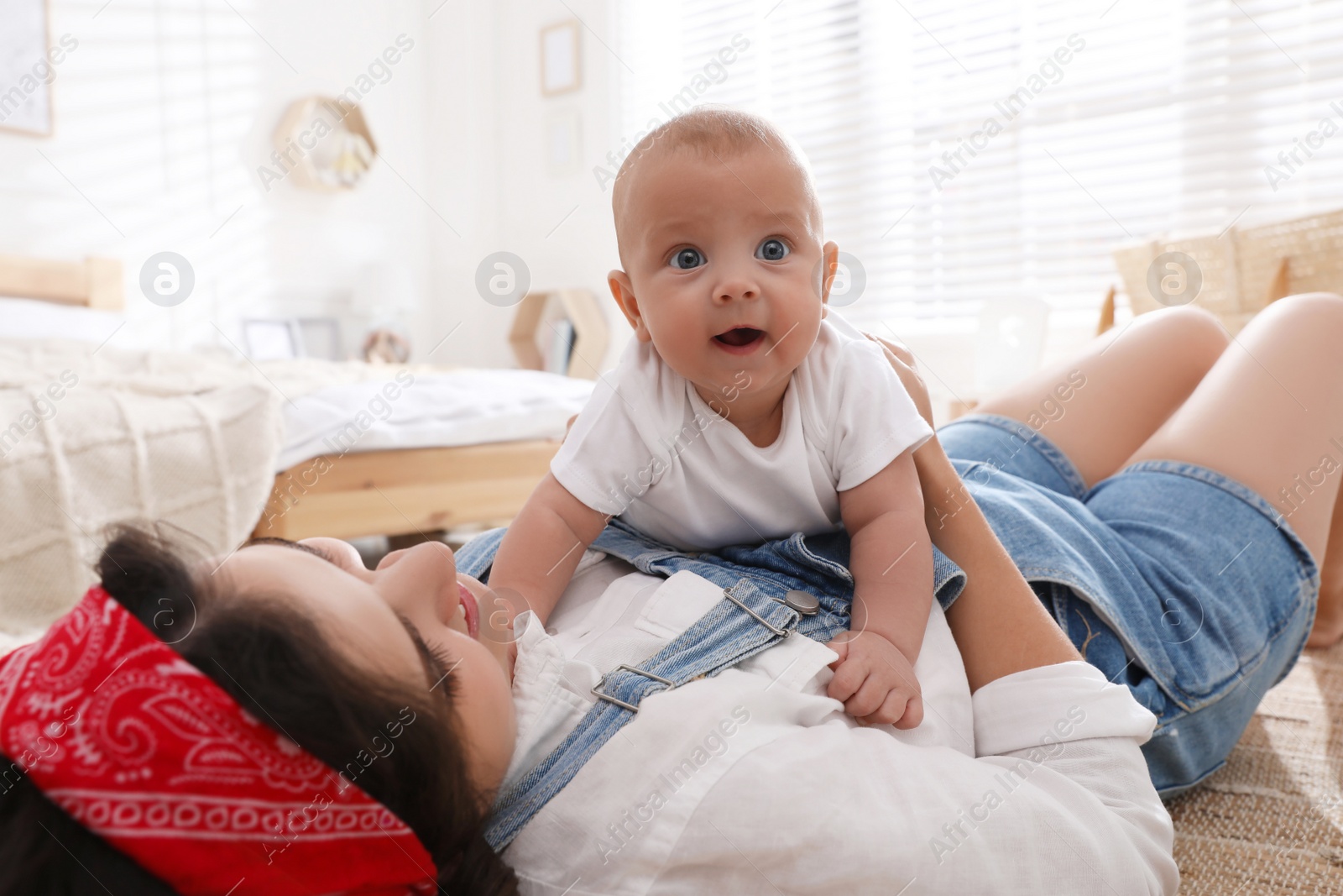 Photo of Young mother with her cute baby on floor at home