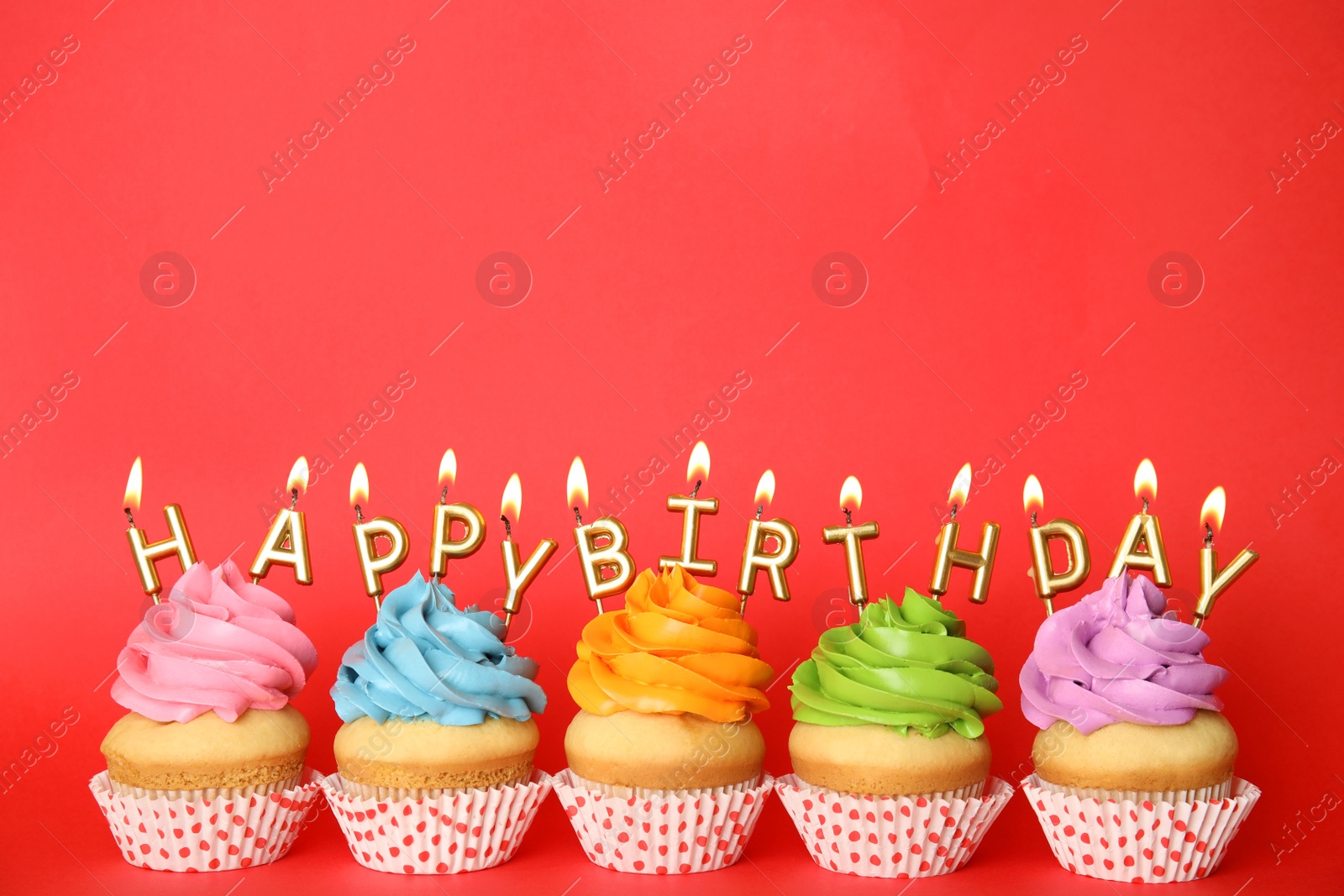 Photo of Birthday cupcakes with burning candles on red background. Space for text