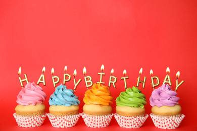 Photo of Birthday cupcakes with burning candles on red background. Space for text