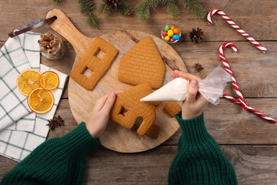 Photo of Woman making gingerbread house at wooden table, top view