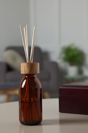 Aromatic reed air freshener and wooden box on light table indoors