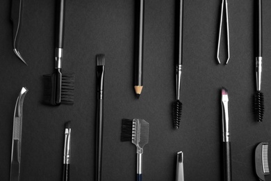 Photo of Set of professional eyebrow tools on black background, flat lay