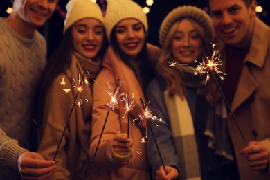 Group of people holding burning sparklers, focus on fireworks