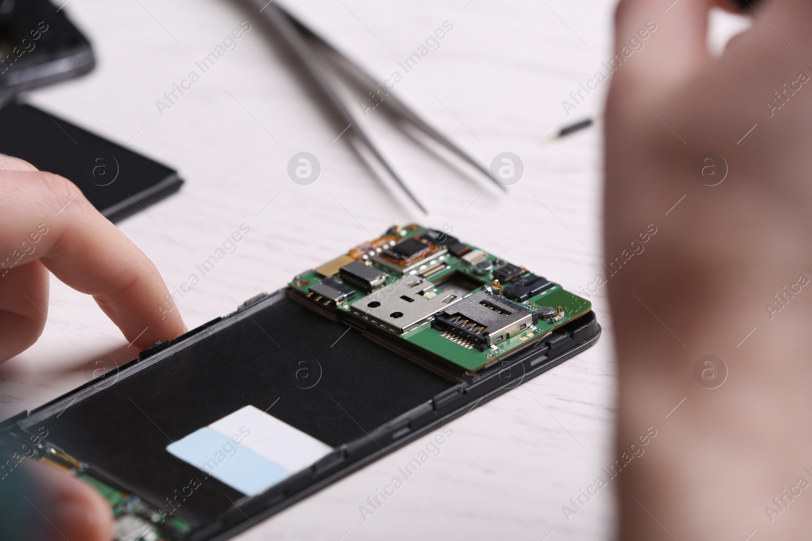 Photo of Technician fixing mobile phone at table, closeup. Device repair service