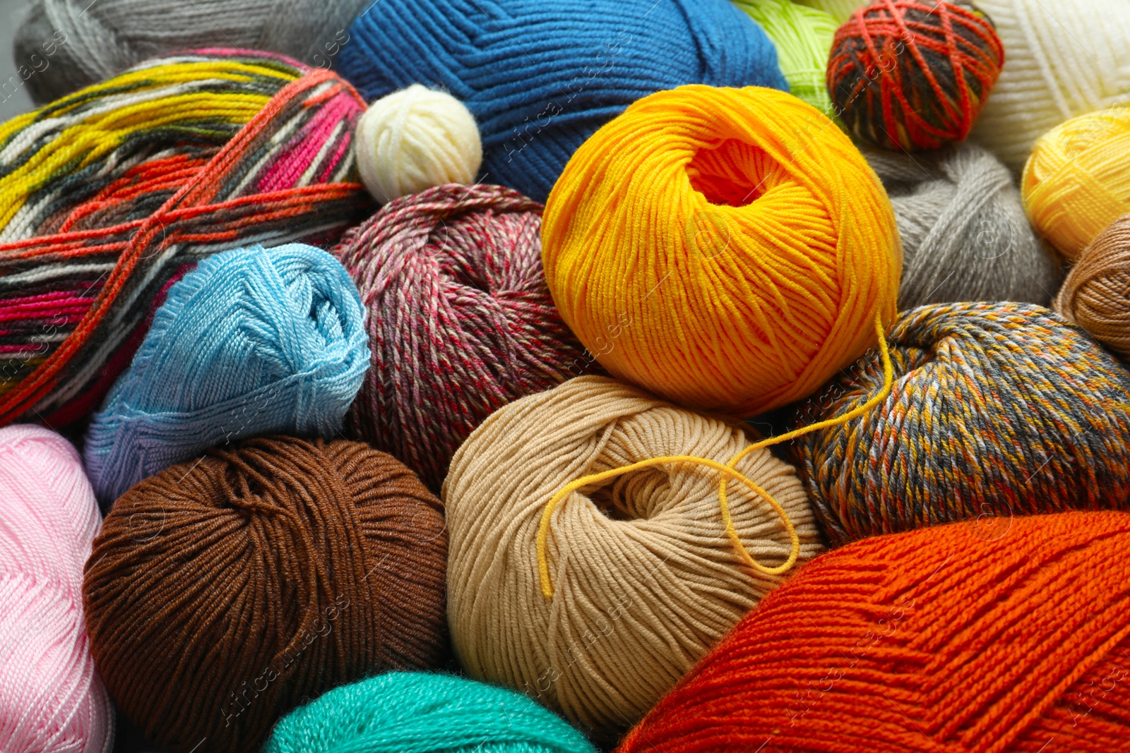 Photo of Different balls of woolen knitting yarns as background, closeup