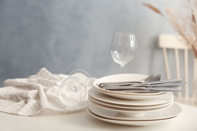Photo of Set of clean dishware, wineglasses and cutlery on white table indoors