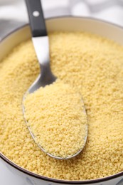 Photo of Bowl and spoon with raw couscous, closeup