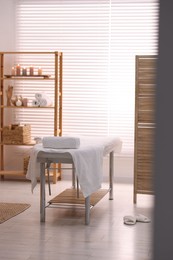 Comfortable massage table with clean towels in spa center