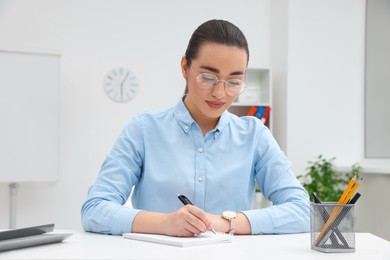 Photo of Young female intern working at table in office