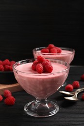 Photo of Delicious raspberry mousse on black wooden table