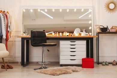 Photo of Makeup room. Stylish dressing table with mirror and chair