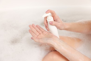 Photo of Woman applying shower gel onto hand in bath indoors, closeup