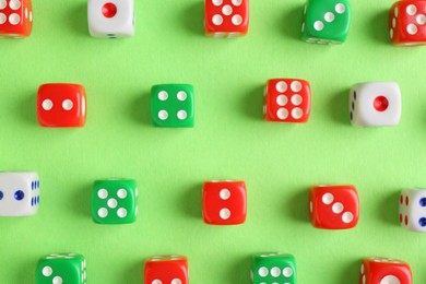 Many color game dices on green background, flat lay