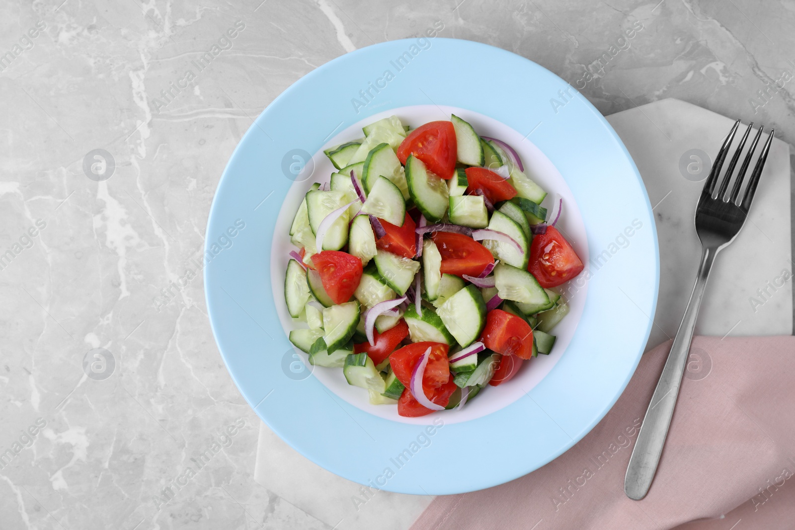 Photo of Plate of vegetarian salad with cucumber, tomato and onion served on table, flat lay