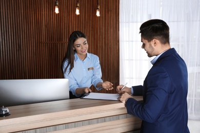 Photo of Receptionist registering client at desk in lobby