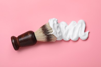 Brush with shaving foam on pink background, top view