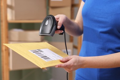 Photo of Parcel packing. Post office worker with scanner reading barcode indoors, closeup