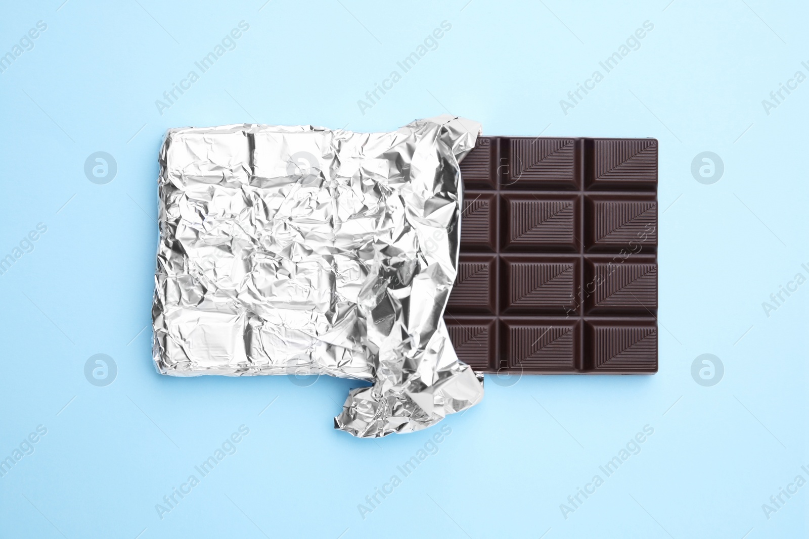 Photo of Tasty chocolate bar on light blue background, top view
