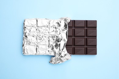 Tasty chocolate bar on light blue background, top view