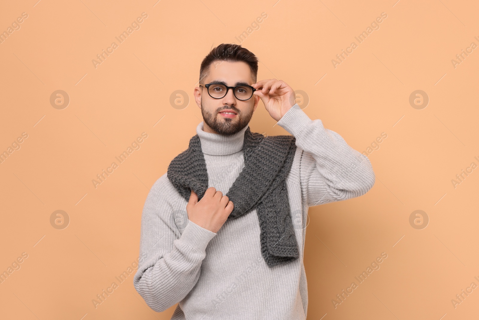 Photo of Handsome man in knitted scarf on beige background