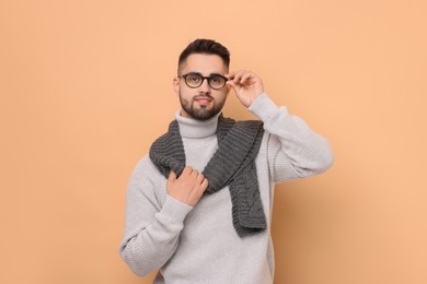 Photo of Handsome man in knitted scarf on beige background