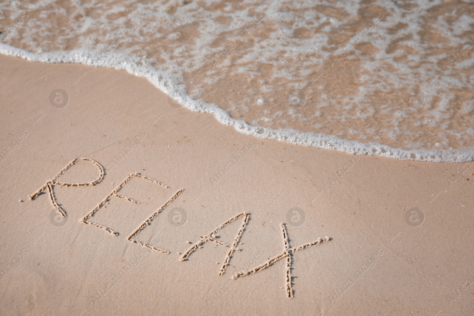 Photo of Word Relax written on sand at beach