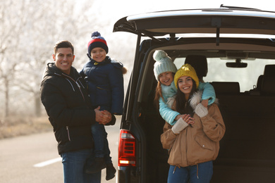 Photo of Happy family with little children near modern car on road