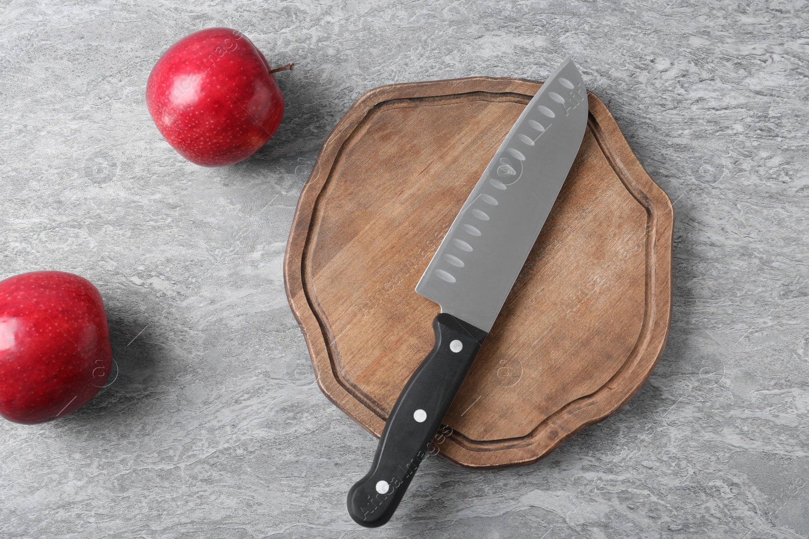 Photo of Cutting board with chef's knife and apples on grey background, flat lay