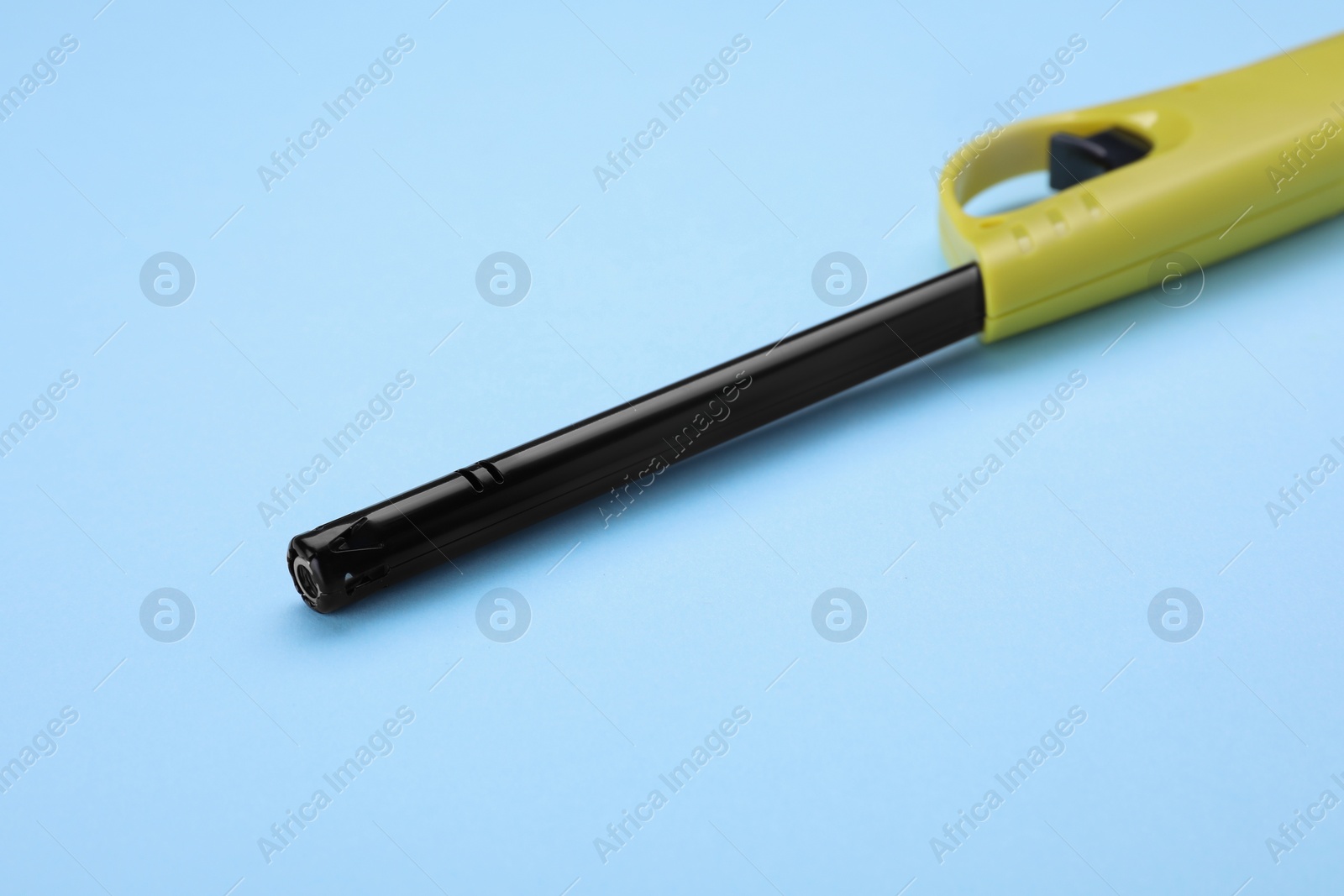 Photo of One gas lighter on light blue background, closeup