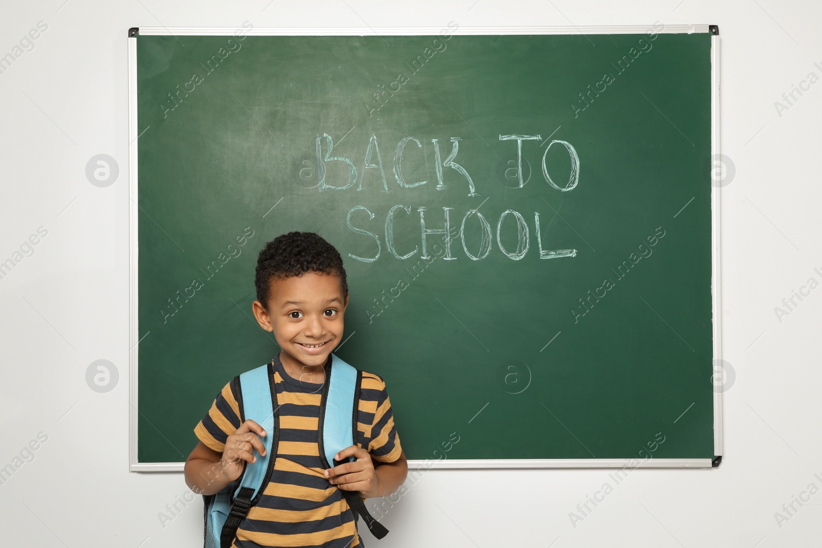 Photo of Little African-American child near chalkboard with text BACK TO SCHOOL