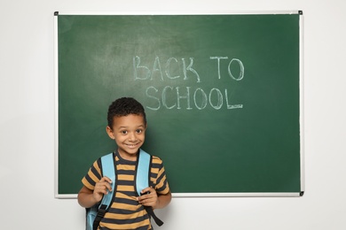 Photo of Little African-American child near chalkboard with text BACK TO SCHOOL