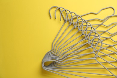 Empty hangers on yellow background, top view. Space for text