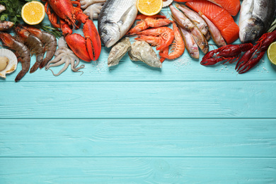 Photo of Fresh fish and different seafood on blue wooden table, flat lay. Space for text
