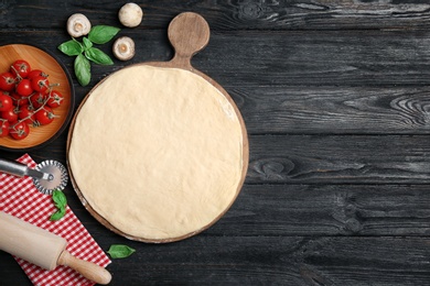 Photo of Flat lay composition with raw dough and ingredients for pizza on wooden background