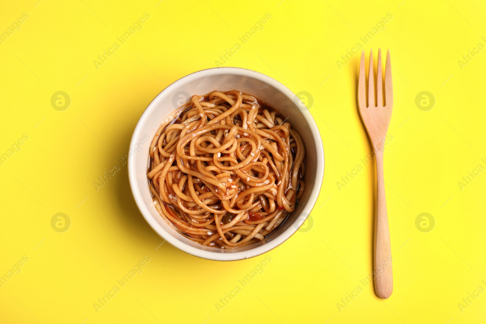 Photo of Cooked noodles and fork on yellow background, flat lay