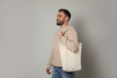 Happy young man with eco bag on light background