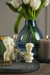 Beautiful sculptural candles, flowers and decor on grey table