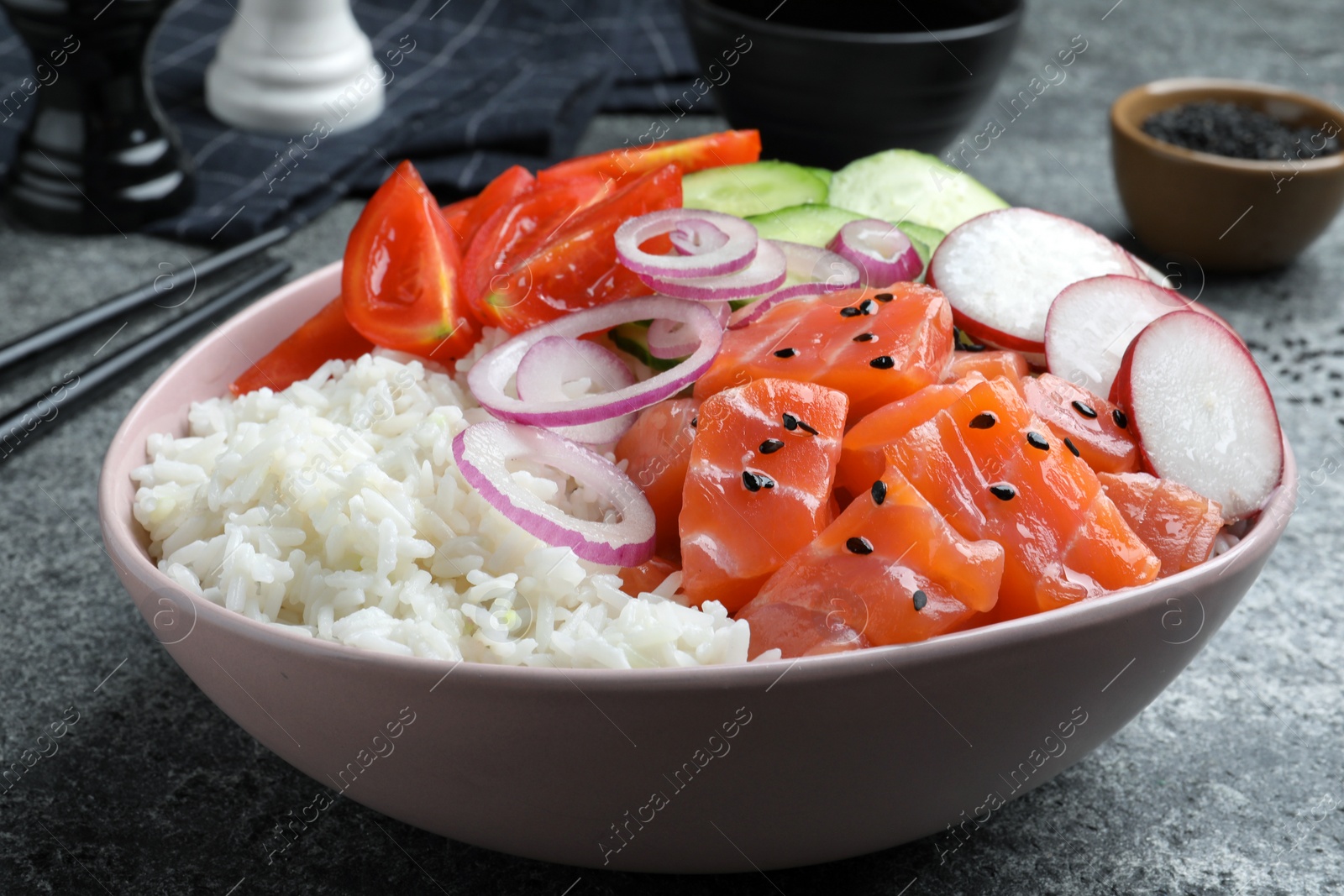 Photo of Delicious poke bowl with salmon and vegetables served on grey table, closeup