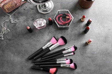 Photo of Makeup products and brushes on grey background